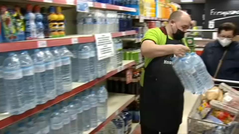 Empleado de supermercado cargando con agua embotellada