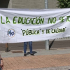 Dos manifestantes portan un pancarta en la que puede leerse 'La Educación no se toca'.