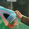 Una persona recicla un envase de vidrio en un contenedor