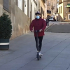 Un joven circula con un patinete eléctrico por una vía urbana