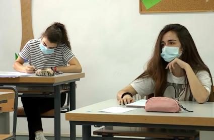 Dos alumnas en sus mesas y atendiendo a clase