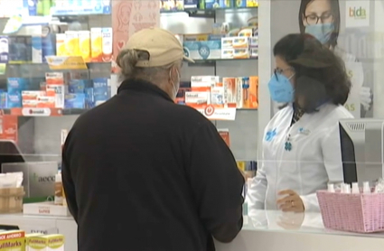 Una farmacéutica atiende a un cliente en una botica de Cáceres