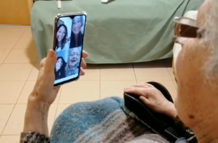 Una anciana recibiendo una videollamada de sus familiares desde una residencia de mayores