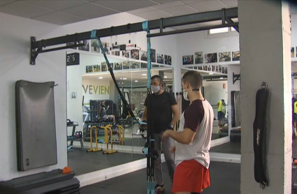 Imagen de dos personas entrenando en un gimnasio durante la pandemia