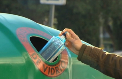 Una persona recicla un envase de vidrio en un contenedor