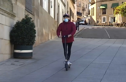 Un joven circula con un patinete eléctrico por una vía urbana