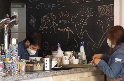 Gente trabajando en el interior de un bar con mascarilla